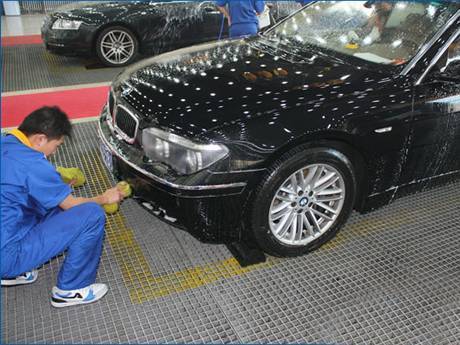 A worker is drying the car on the steel grating floor.
