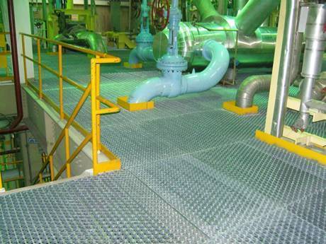 Steel riveted grating floor and various metal pipes vertical through floor.