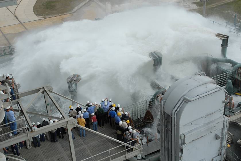 Many people standing on the steel grating floor of rocket launch pad.