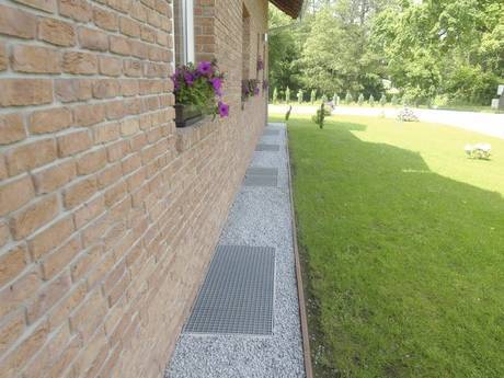 Steel grating drainage grid laid on the floor behind the house wall.