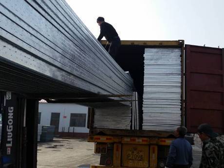 The forklift and workers are loading the container.