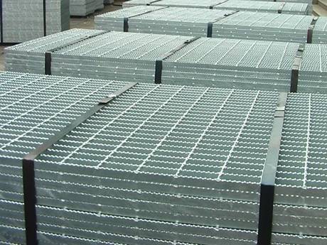 Several bundles of steel bar grating on the ground.